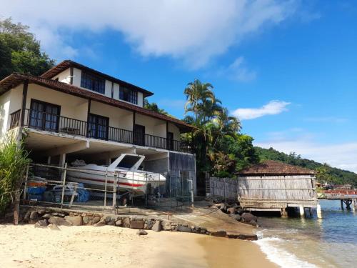 ein Haus am Strand mit einem Boot in der Unterkunft Suites Ponta Leste in Angra dos Reis