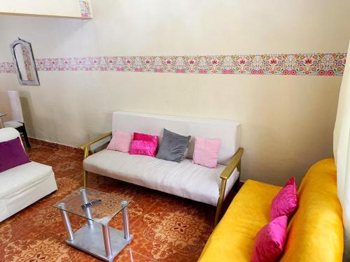 ein Wohnzimmer mit einer weißen Couch mit bunten Kissen in der Unterkunft Alojamiento a 6 cuadras de la plaza in Cusco