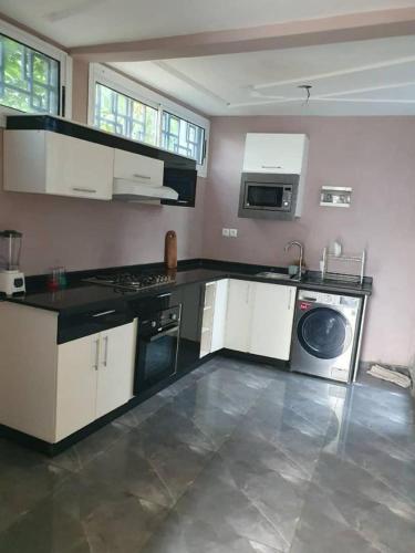 a kitchen with white cabinets and a washer and dryer at Paradis des anges in Yaoundé