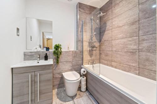 a bathroom with a tub and a toilet and a sink at Luxury Unit Sleeps 5 Ensuite 2 bath Games FREE WI-FI LEICESTER CITY CENTRE in Leicester