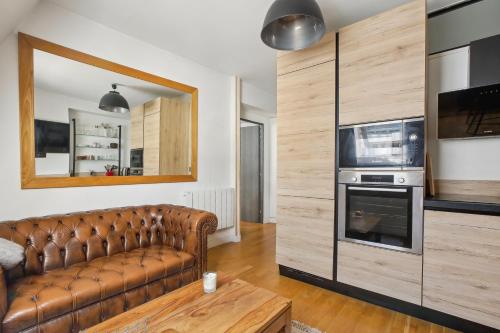 un salon avec un canapé en cuir marron et un micro-ondes dans l'établissement Trocadéro/Victor Hugo - Confort absolu, à Paris