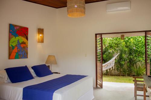een slaapkamer met een bed en een glazen schuifdeur bij Pousada Vila Cobé in Japaratinga
