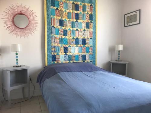 - une chambre avec un lit bleu et un mur avec des livres dans l'établissement La petite maison, à Denneville