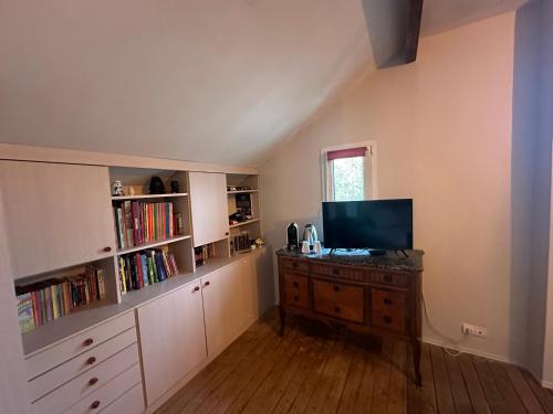 Habitación con escritorio, TV y estanterías de libros. en 21, en Melun