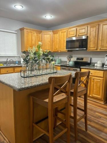 a kitchen with wooden cabinets and a island with two chairs at Serenity Cottage in Ocean Springs