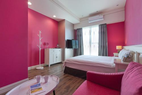 a hotel room with pink walls and a bed and a table at Sommer 19 B&B in Luodong