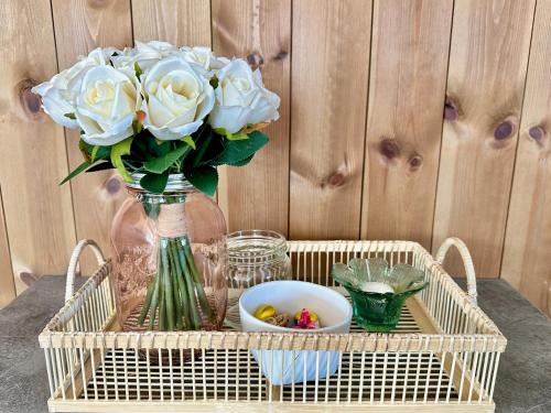a tray with a vase with white roses in it at Leknes Airport Apartment in Leknes