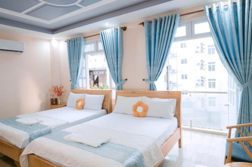 2 Betten in einem Zimmer mit blauen Vorhängen in der Unterkunft Calido Hotel Vung Tau in Xã Thang Tam