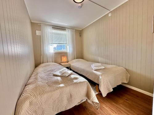 two beds in a small room with a window at Leknes Airport Apartment in Leknes