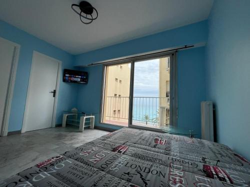 une chambre avec un grand lit et une grande fenêtre dans l'établissement Vue mer, à Nice