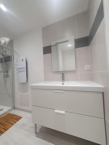 une salle de bain blanche avec un lavabo et un miroir dans l'établissement Nyons : appartement refait à NEUF, à Nyons