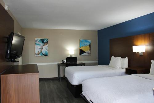 a hotel room with two beds and a flat screen tv at Baymont by Wyndham Abilene in Abilene