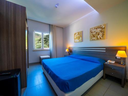 Un dormitorio con una cama azul y una ventana en Hotel Eden Park Cilento, en Policastro Bussentino