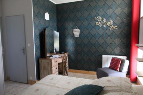a bedroom with a bed and a desk and a chair at La ferme aux chats in Formigny