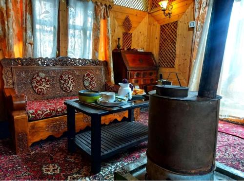 a living room with a table and a stove at Pasadona Floating Houseboat in Srinagar