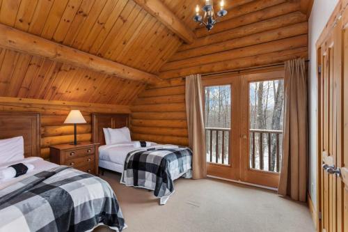 um quarto com 2 camas num chalé de madeira em Chalet Zurri em Labelle
