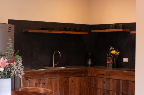 een keuken met een wastafel en een zwarte muur bij Xamira Tulum Studios in Tulum