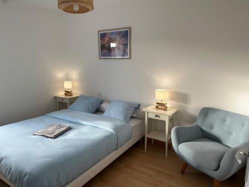 ein Schlafzimmer mit einem Bett, einem Stuhl und einer Lampe in der Unterkunft La garenne, près des commerces in Saint-Jean-de-Monts