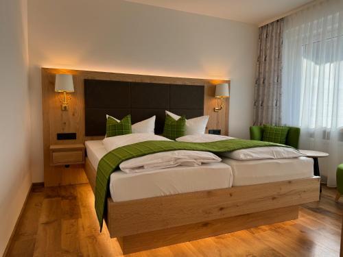 a bedroom with a large bed and a green chair at Hotel Tannenhof in Bad Harzburg
