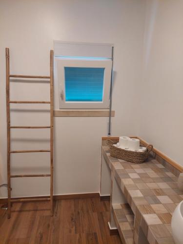 eine Küche mit einer Theke mit einem Fenster und einem Regal in der Unterkunft Quinta das Laranjeiras in Marinhais