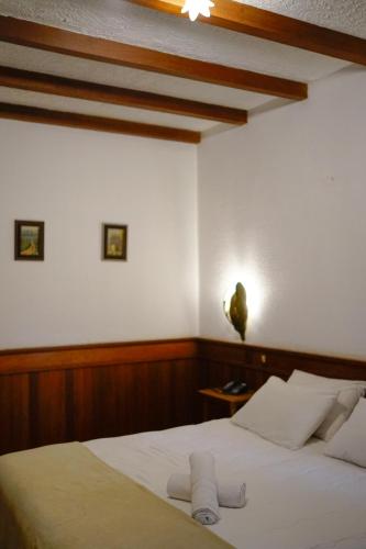 a bedroom with a bed with white sheets and a ceiling at Campos Hotel do Sol in Campos do Jordão