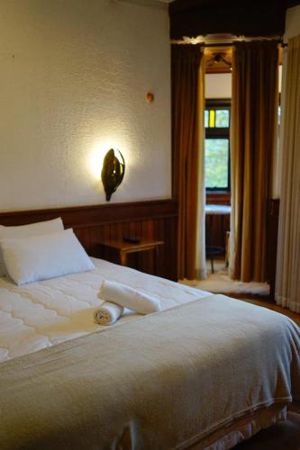 a bedroom with a bed with white sheets and a window at Campos Hotel do Sol in Campos do Jordão