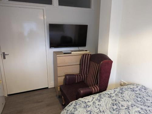 a bedroom with a chair and a tv and a bed at House in Leeds