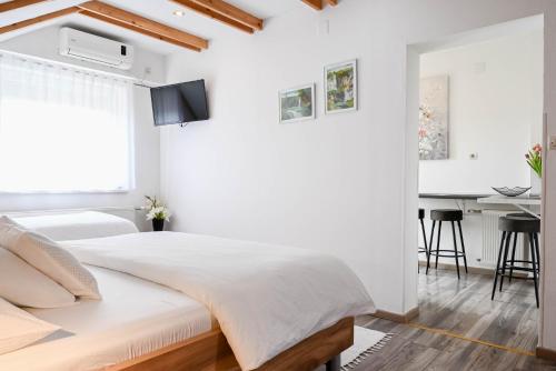a white bedroom with a large bed and a table at Guesthouse Rubcic in Rakovica