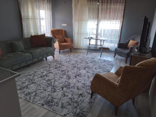 ein Wohnzimmer mit einem Sofa, Stühlen und einem Teppich in der Unterkunft Güven Rezidans in Buca