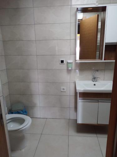 ein Badezimmer mit einem WC, einem Waschbecken und einem Spiegel in der Unterkunft Güven Rezidans in Buca