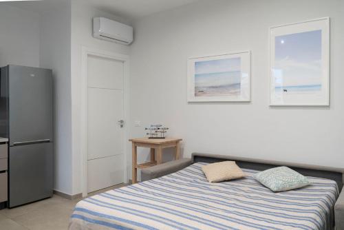 a white bedroom with a bed and a refrigerator at Le case di vada/ Appartamento le Tamerici in Vada