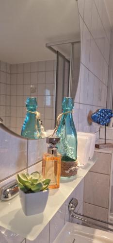 - une salle de bains avec 2 bouteilles de verre vert sur une étagère dans l'établissement Haus Vineta, à Barth