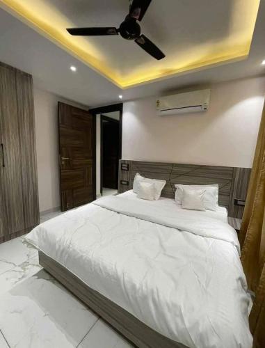a bedroom with a white bed with a ceiling fan at Your home stay in Rishīkesh
