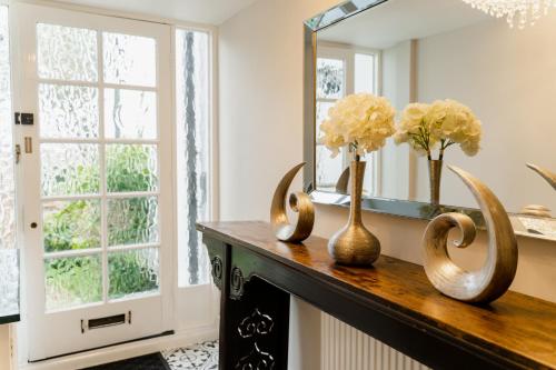 a mirror and vases on a table in a room at Spacious Chester City Centre Stylish Townhouse. W/ Parking in Chester