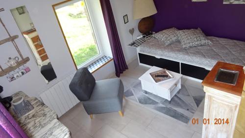 a bedroom with a bed and a chair and a window at La ferme aux chats in Formigny