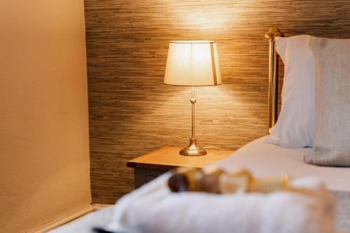a hotel room with a bed and a lamp on a table at Spacious Chester City Centre Stylish Townhouse. W/ Parking in Chester