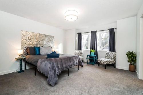 a bedroom with a large bed and two windows at Vibrant Modern Oasis - Long Stays - Netflix - Wi-Fi in Edmonton