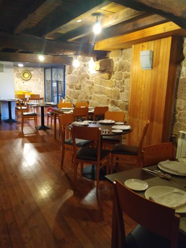 un restaurante con mesas y sillas y una pared de piedra en Pensión rural Pallabarro, en Allariz