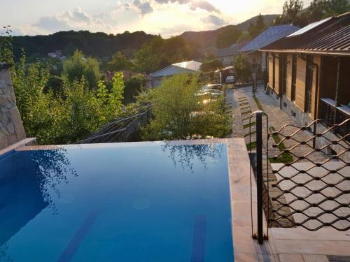 a blue swimming pool with a view of a house at Felix Pension in Băile Govora