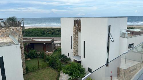 a white building with the ocean in the background at Apartamento Chique frente ao mar in Flecheiras
