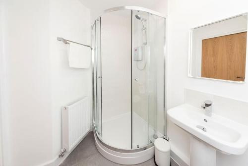 a white bathroom with a shower and a sink at Wakefield City Centre 1 minute walk to station 2 bedroom townhouse with parking in Wakefield