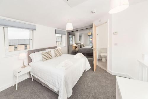 a white bedroom with a bed and a living room at Wakefield City Centre 1 minute walk to station 2 bedroom townhouse with parking in Wakefield