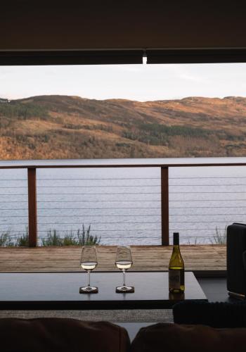 two wine glasses sitting on a table in front of a window at Shoreland Lodges - Cherry Lodge in Fort Augustus