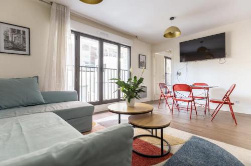a living room with a couch and a table with chairs at L'Escapade Paris in Le Kremlin-Bicêtre