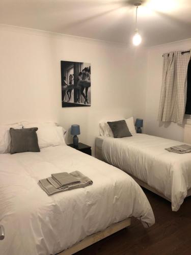 a bedroom with two beds with towels on them at Mill Hill Modern 3 Bedroom Apartment in Mill Hill