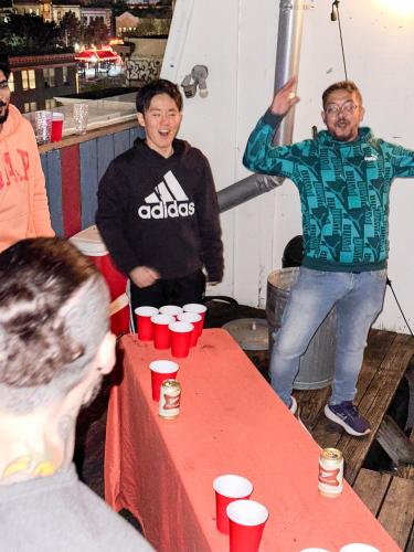 a group of men standing around a table with red cups at ITH San Francisco Pacific Tradewinds Backpacker Hostel in San Francisco