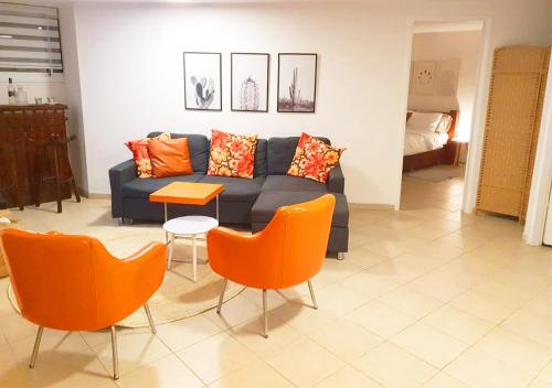 a living room with a blue couch and orange chairs at Spacious and Peaceful 2BD with a Garden & Parking in Gan H̱ayyim