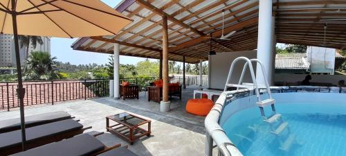 a patio with a swimming pool and an umbrella at Mamma Mia Villa and Cafeteria in Unawatuna