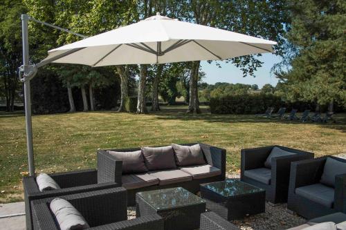 une terrasse avec un canapé et un parasol dans l'établissement Grande maison de caractère avec Piscine, à Volesvres