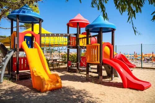 un parque infantil con un colorido equipo de juegos en la arena en Villaggio Turistico Grotta dell'Acqua, en Peschici